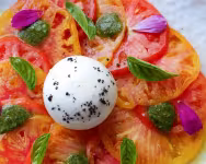 Assiette de tomates anciennes, burrata, pesto et fleurs comestibles