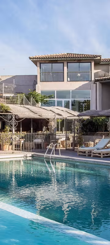 Piscine bordée de transats, devant la terrasse du restaurant et les chambres de l'hôtel