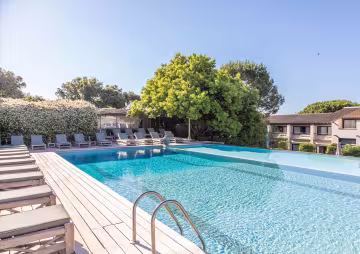 Piscine à débordement bordée de transats, sous un ciel bleu